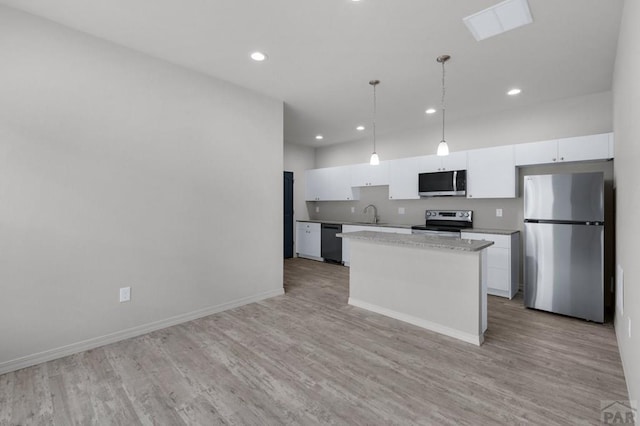 280 W Harmony Dr, Pueblo West, CO 81007 - kitchen with baseboards, a kitchen island, light wood-style floors, white cabinets, and appliances with stainless steel finishes
