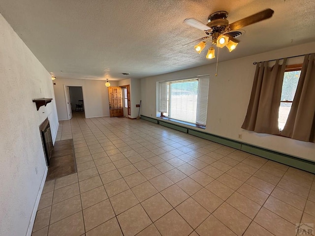 480 W 9th Ave, Lamar, CO 81073 - unfurnished living room with a ceiling fan, a textured ceiling, light tile patterned flooring, a glass covered fireplace, and baseboards