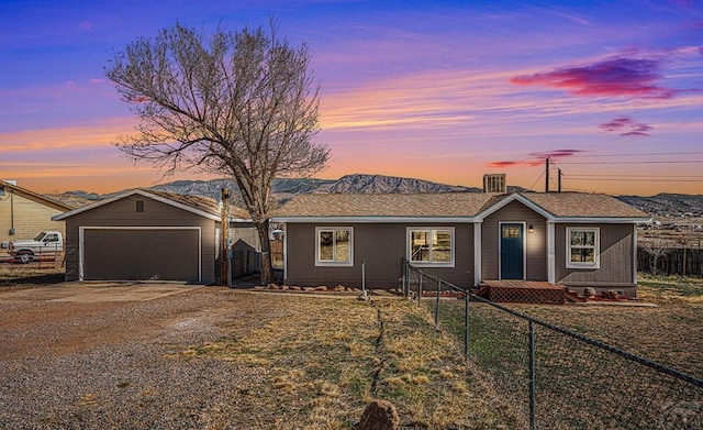 single story home featuring a garage, fence private yard, a mountain view, and an outdoor structure