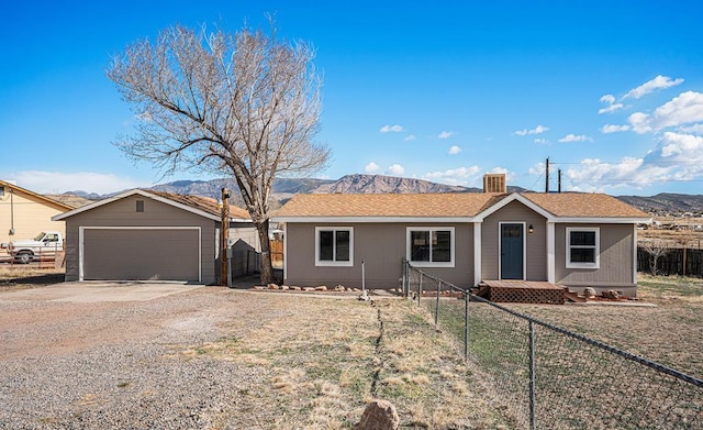 single story home with a garage, fence, a mountain view, and an outbuilding