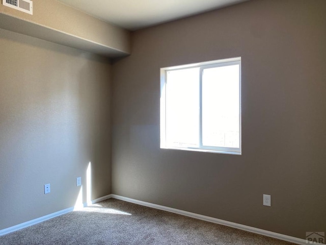 carpeted spare room featuring visible vents and baseboards