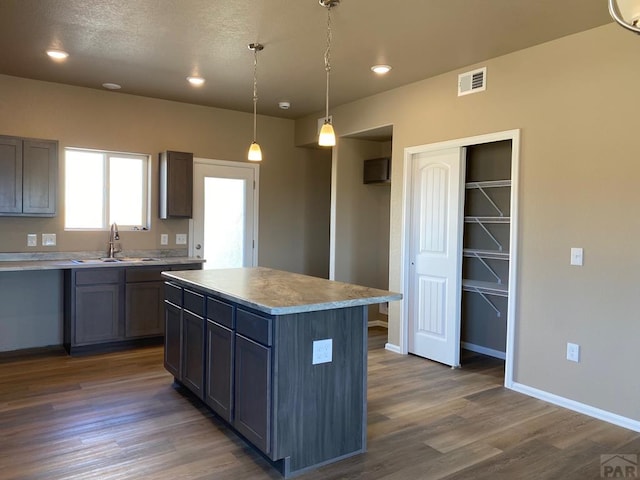 kitchen with dark wood finished floors, visible vents, baseboards, and a sink