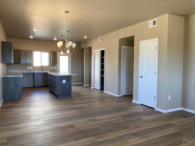 kitchen featuring a center island, baseboards, an inviting chandelier, dark wood-style floors, and a sink