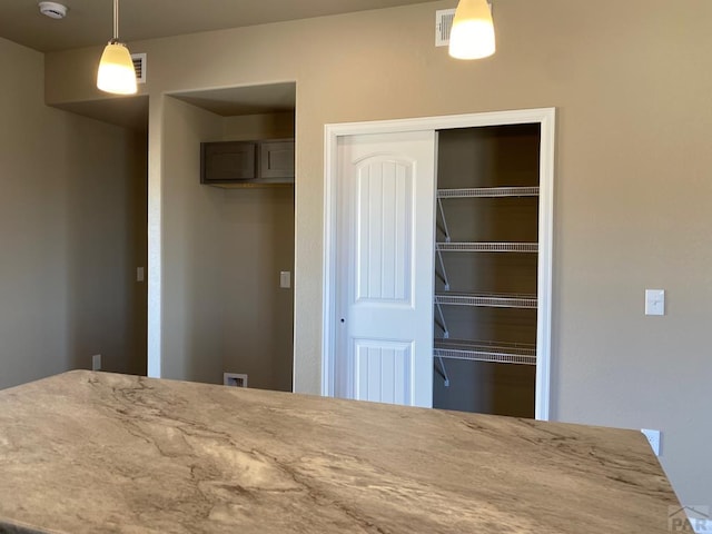 interior space with pendant lighting and light stone countertops