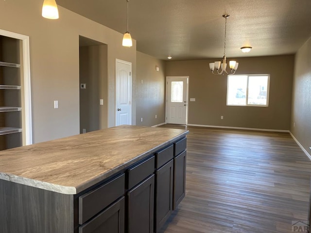 kitchen with a notable chandelier, pendant lighting, a center island, and dark wood-type flooring