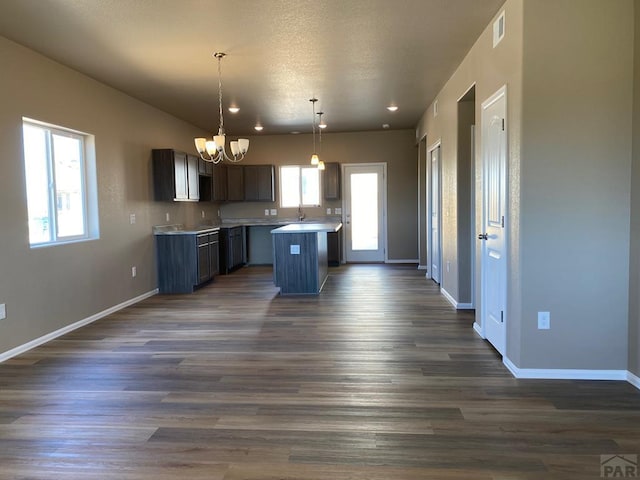 kitchen with visible vents, a kitchen island, baseboards, and dark wood-style flooring