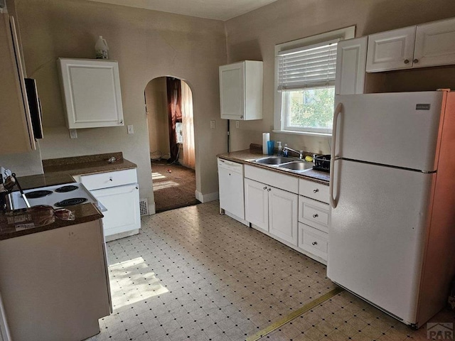 kitchen with arched walkways, light floors, white appliances, and a sink