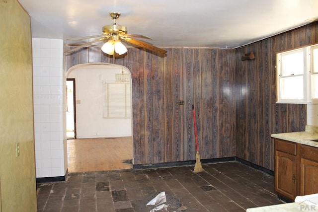 unfurnished room with dark wood-style flooring, ceiling fan, and wooden walls