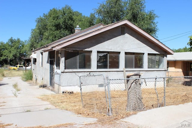 view of side of home featuring a fenced front yard and stucco siding