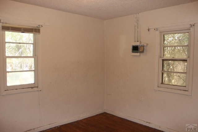 spare room with a textured ceiling and dark wood-type flooring