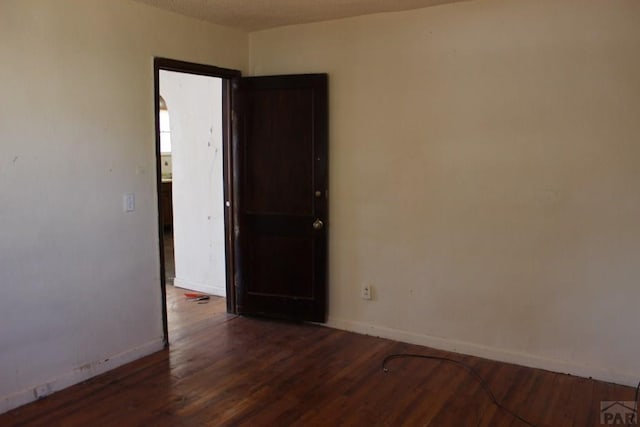 empty room featuring wood finished floors and baseboards