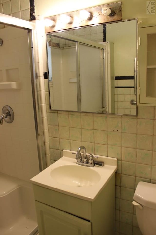 full bathroom with tile walls, decorative backsplash, toilet, vanity, and walk in shower