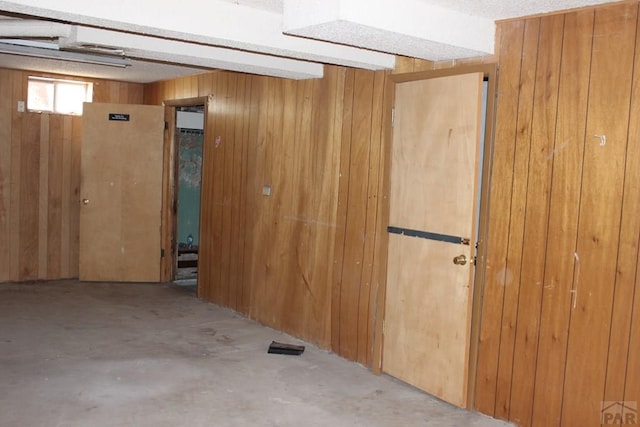 spare room featuring wood walls and unfinished concrete floors