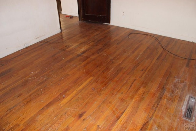 empty room featuring hardwood / wood-style flooring and visible vents