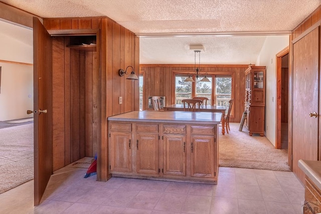 kitchen with light countertops, brown cabinetry, light carpet, wooden walls, and a peninsula