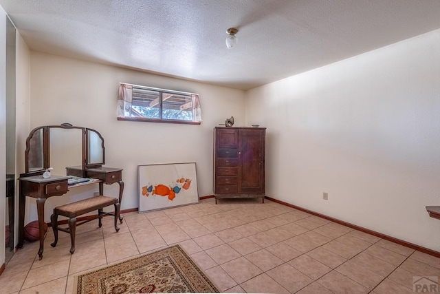 living area featuring light tile patterned floors, baseboards, and a textured ceiling