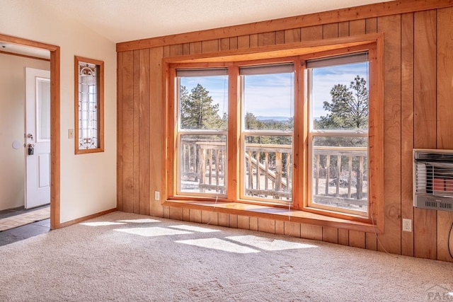 empty room featuring heating unit, wooden walls, and carpet flooring