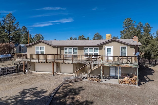 view of front of home with driveway, a chimney, stairway, an attached garage, and stucco siding