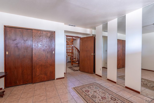 interior space featuring stairway, baseboards, light tile patterned floors, and visible vents