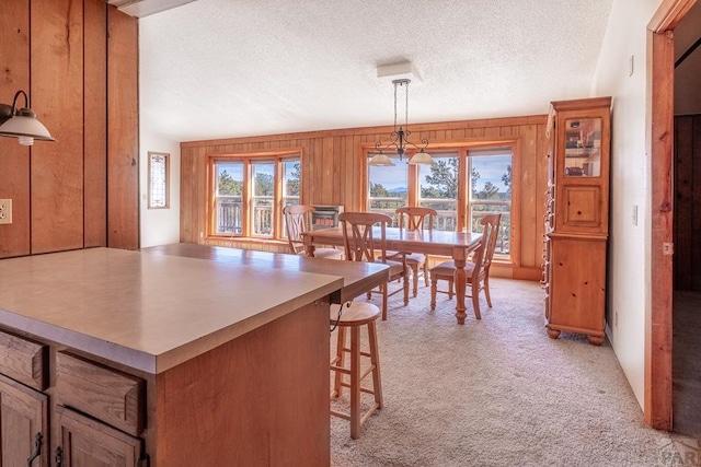 kitchen featuring wooden walls, a kitchen breakfast bar, a textured ceiling, and light colored carpet