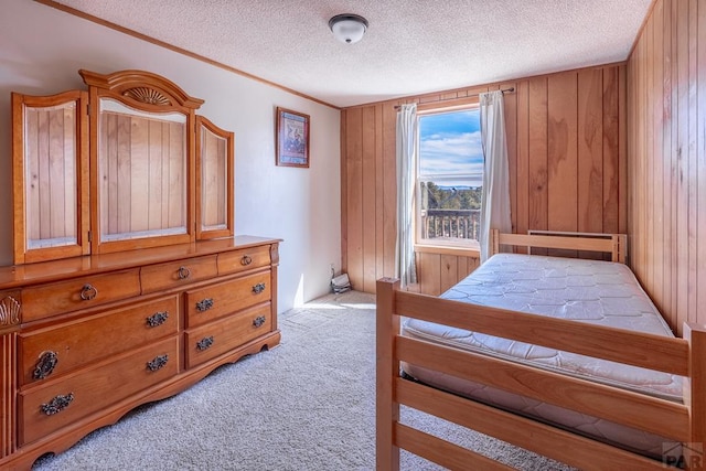 bedroom with light colored carpet, wood walls, and a textured ceiling