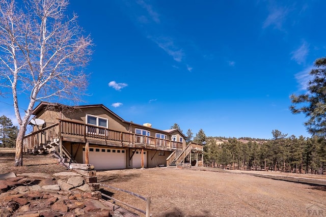 view of front of property with a garage, stucco siding, a wooden deck, and stairs