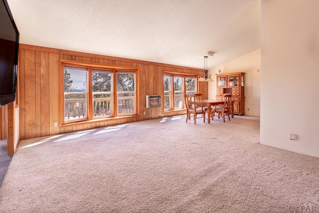 carpeted dining room with a textured ceiling, wood walls, lofted ceiling, and heating unit