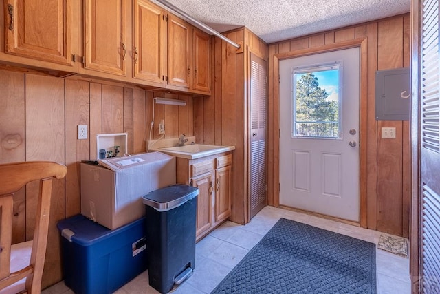 washroom featuring washer hookup, cabinet space, wood walls, a sink, and a textured ceiling