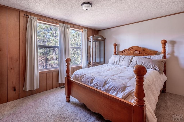 carpeted bedroom with a textured ceiling, crown molding, multiple windows, and wooden walls