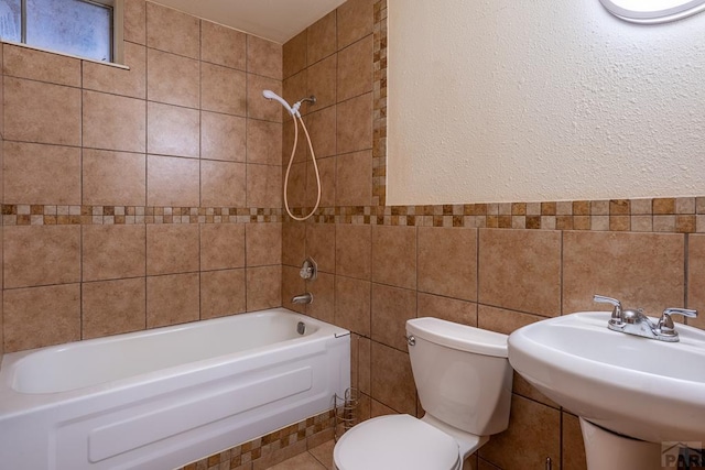 bathroom featuring a sink, tile walls, toilet, and bathing tub / shower combination