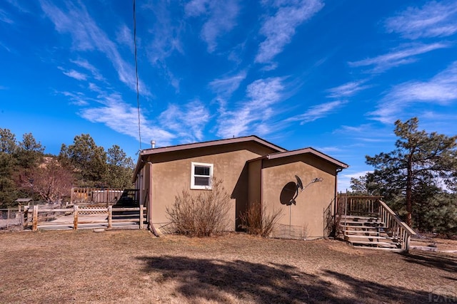 exterior space with a wooden deck, stairway, and stucco siding