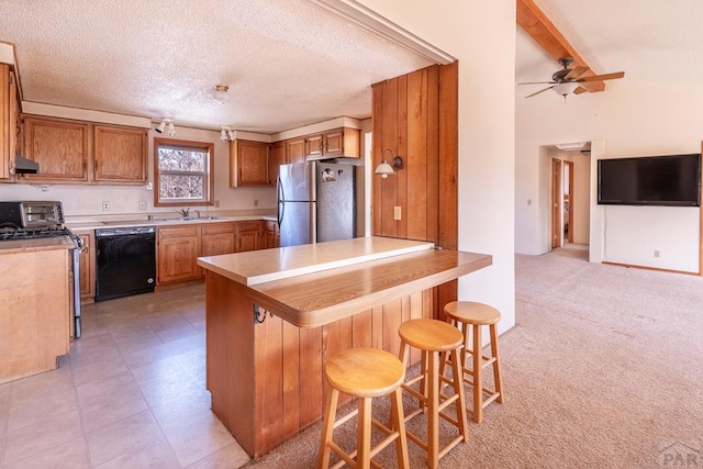 kitchen with light carpet, stainless steel appliances, a peninsula, a sink, and brown cabinetry