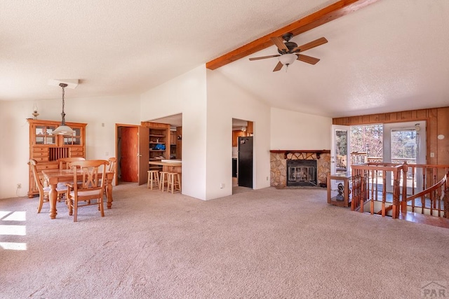 carpeted living room featuring a ceiling fan, a textured ceiling, a fireplace, high vaulted ceiling, and beam ceiling