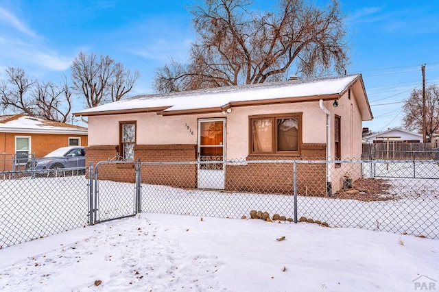 view of front of home featuring brick siding, a fenced front yard, and stucco siding