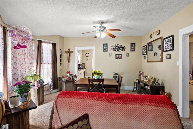 carpeted dining room with a ceiling fan, a textured ceiling, and baseboards