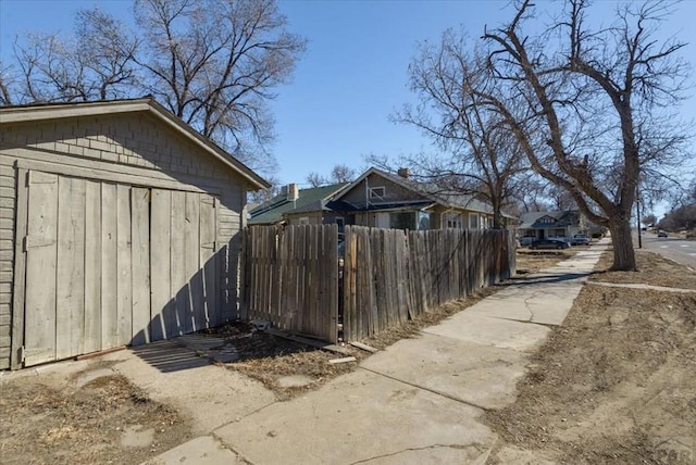 exterior space featuring a residential view, fence, and an outbuilding