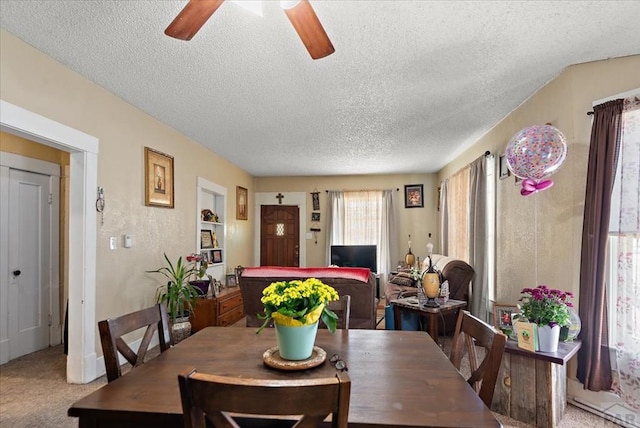 dining room featuring a ceiling fan, a textured ceiling, and light colored carpet