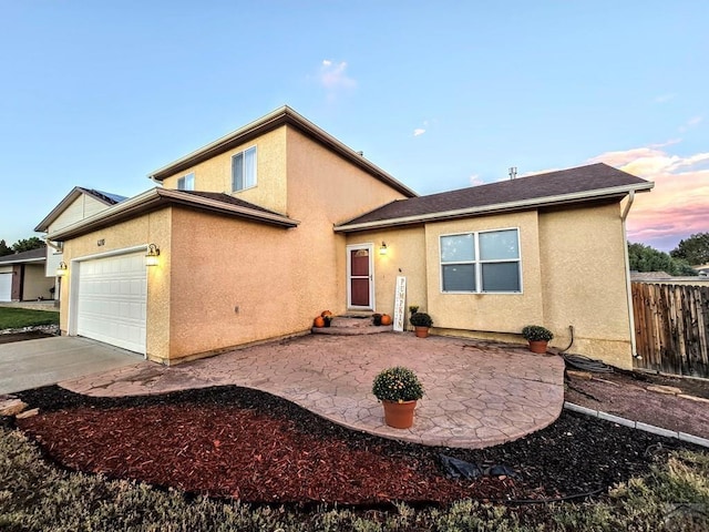 view of front of home with a garage, fence, driveway, and stucco siding