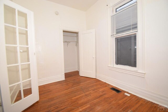 unfurnished bedroom with baseboards, a closet, visible vents, and wood finished floors