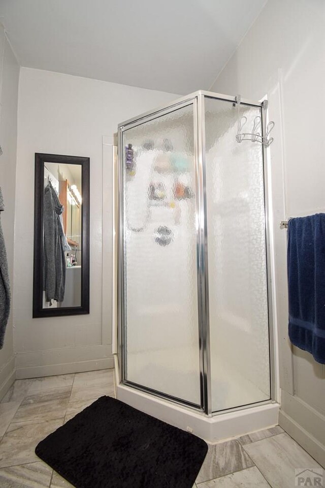 full bathroom with a stall shower and baseboards