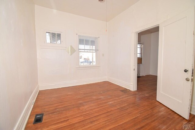 empty room with baseboards, visible vents, and wood finished floors