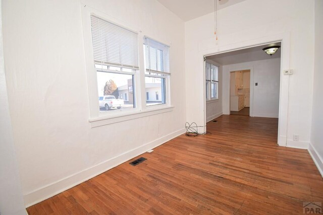 unfurnished room featuring wood finished floors, visible vents, and baseboards