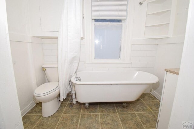 full bath with toilet, tile patterned flooring, a freestanding bath, and vanity