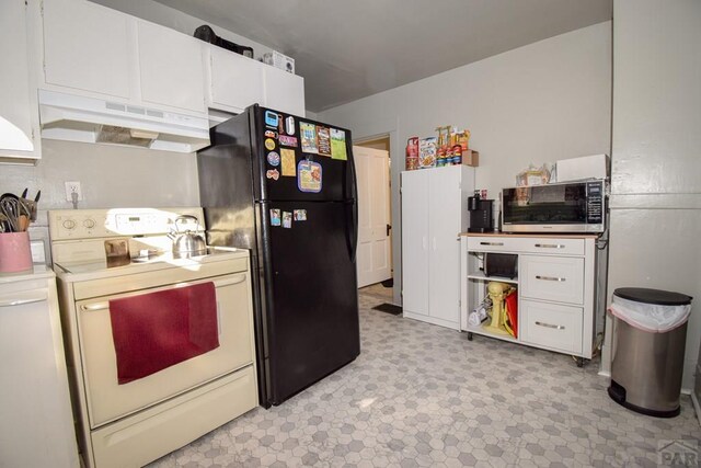 kitchen featuring electric stove, stainless steel microwave, freestanding refrigerator, light countertops, and under cabinet range hood