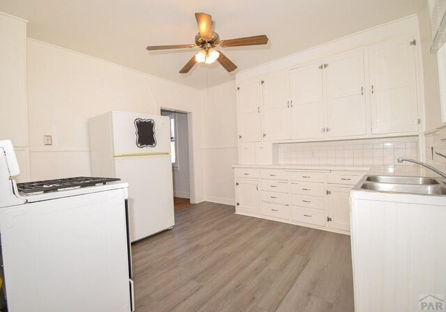 kitchen with white appliances, a sink, light wood-style floors, white cabinets, and light countertops