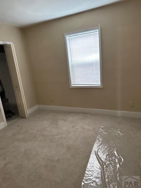 unfurnished room featuring carpet floors and baseboards