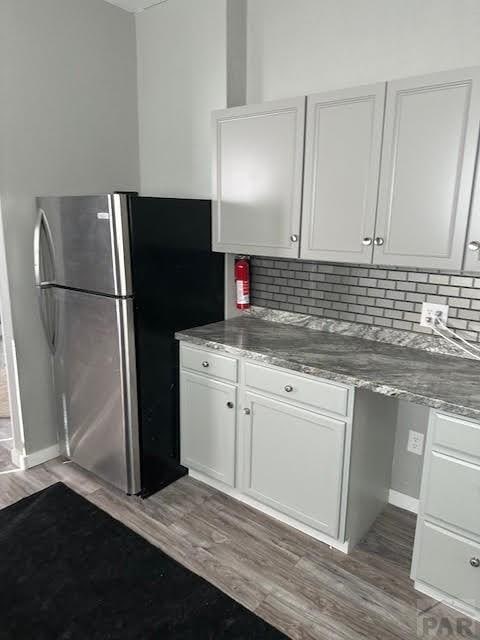 kitchen with white cabinetry, wood finished floors, and freestanding refrigerator