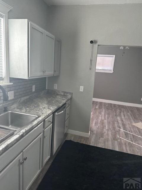 kitchen featuring backsplash, white cabinets, a sink, wood finished floors, and dishwasher