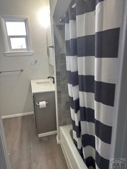 full bath featuring baseboards, shower / bathtub combination with curtain, vanity, and wood finished floors