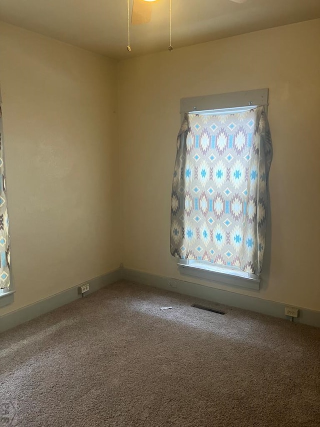 carpeted spare room with visible vents and baseboards